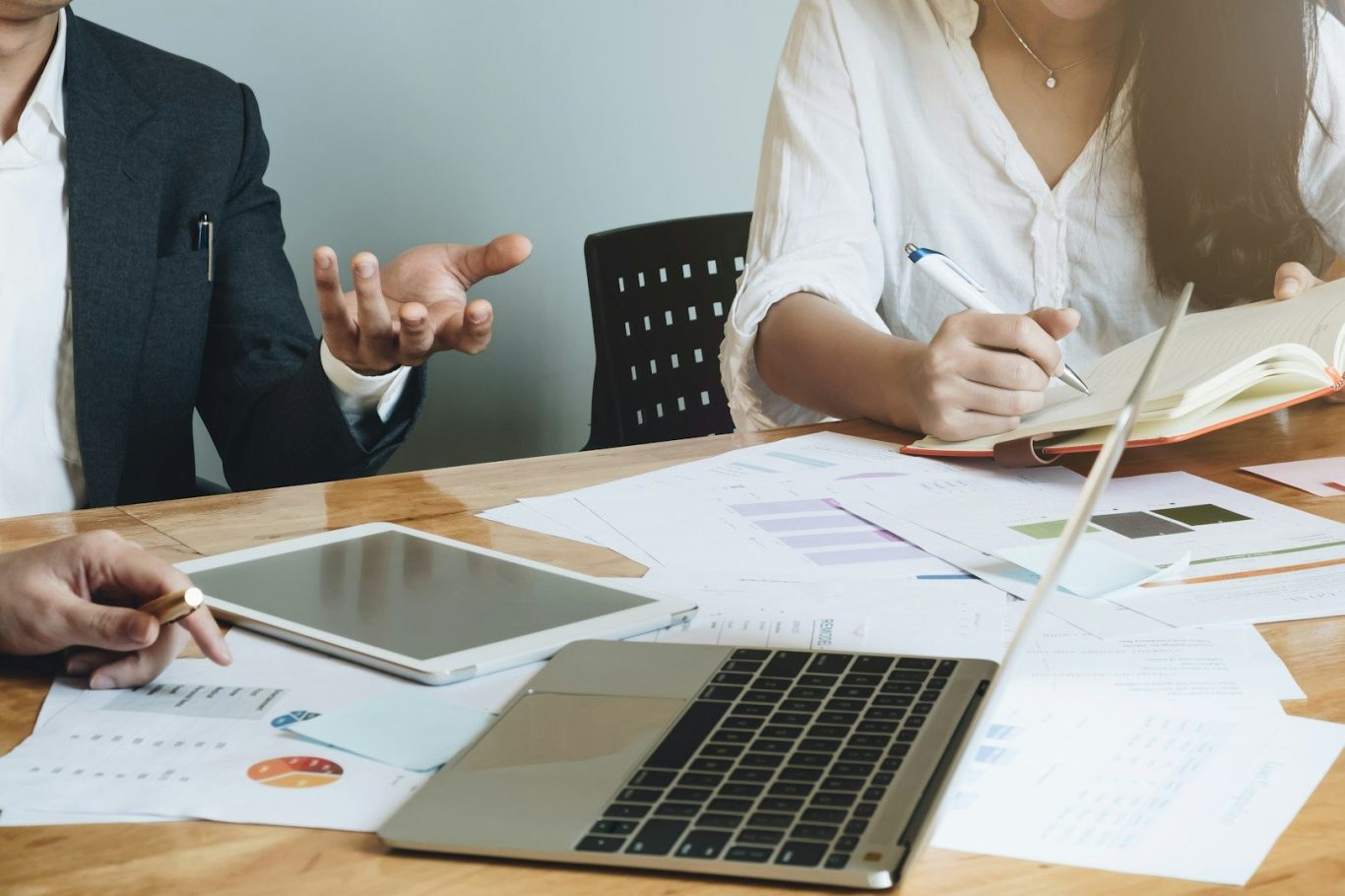 Online Konfliktcoaching Zwei Personen diskutieren am Tisch, Laptops und Unterlagen sind sichtbar.